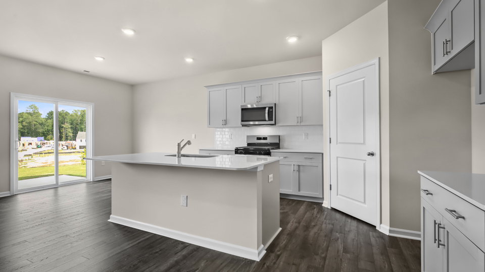 kitchen with quartz counters, kitchen island, pantry, stainless steel appliances