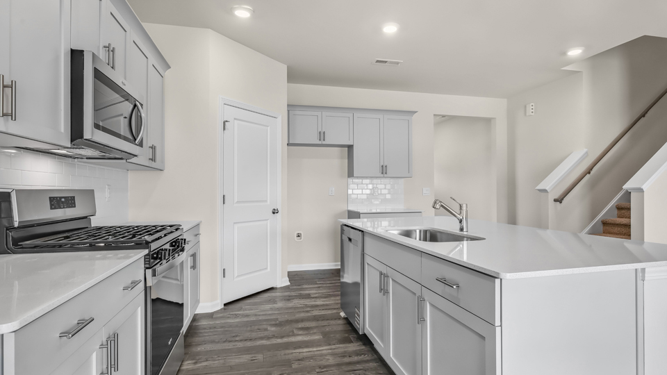 kitchen with quartz counters, kitchen island, pantry, stainless steel appliances