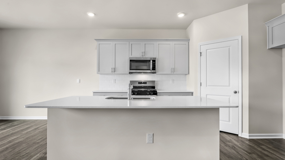 kitchen with quartz counters, kitchen island, pantry, stainless steel appliances