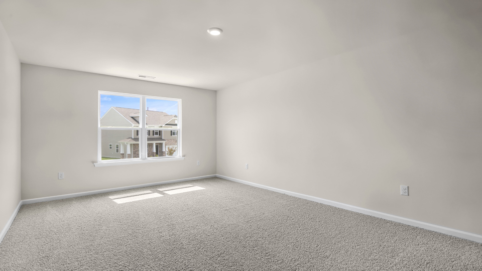 primary bedroom with two windows and carpeting, attached bath