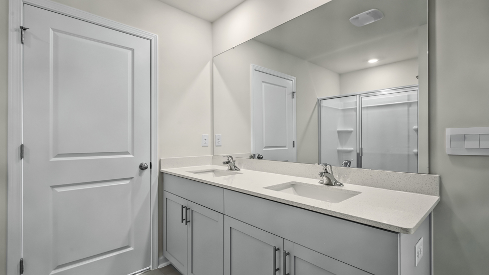 primary bathroom with walk in shower and dual vanity sinks
