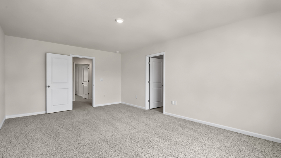 primary bedroom with two windows and carpeting, attached bath