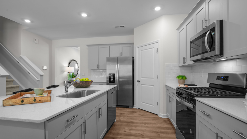 kitchen with quartz counters, kitchen island, pantry, stainless steel appliances