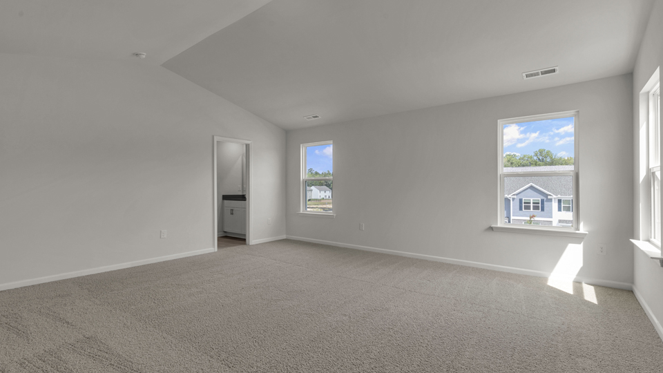 primary bedroom with two windows and carpeting, attached bath