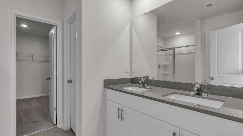 primary bathroom with walk in shower and dual vanity sinks