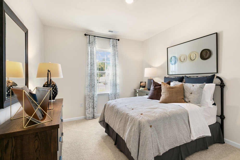 primary bedroom with two windows and carpeting, attached bath