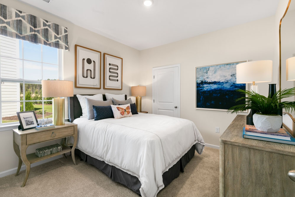 primary bedroom with two windows and carpeting, attached bath
