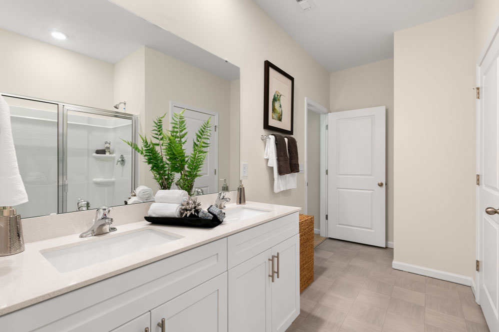 primary bathroom with walk in shower and dual vanity sinks