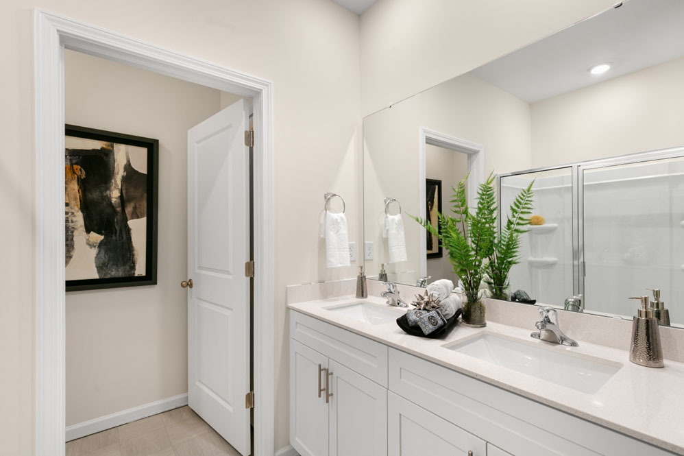primary bathroom with walk in shower and dual vanity sinks