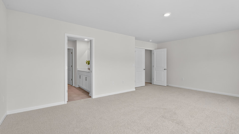primary bedroom with two windows and carpeting, attached bath