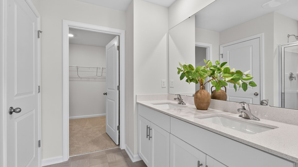 primary bathroom with walk in shower and dual vanity sinks