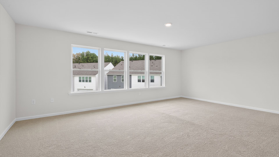 primary bedroom with two windows and carpeting, attached bath