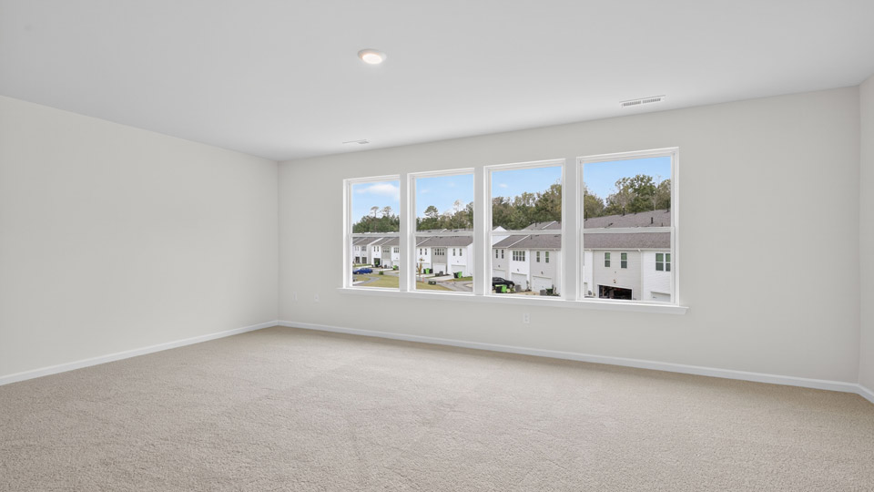 primary bedroom with two windows and carpeting, attached bath