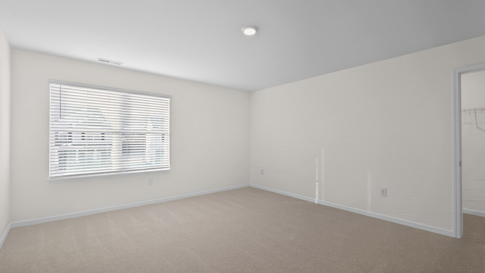 Primary bedroom with carpet floors and windows with access to the primary bathroom