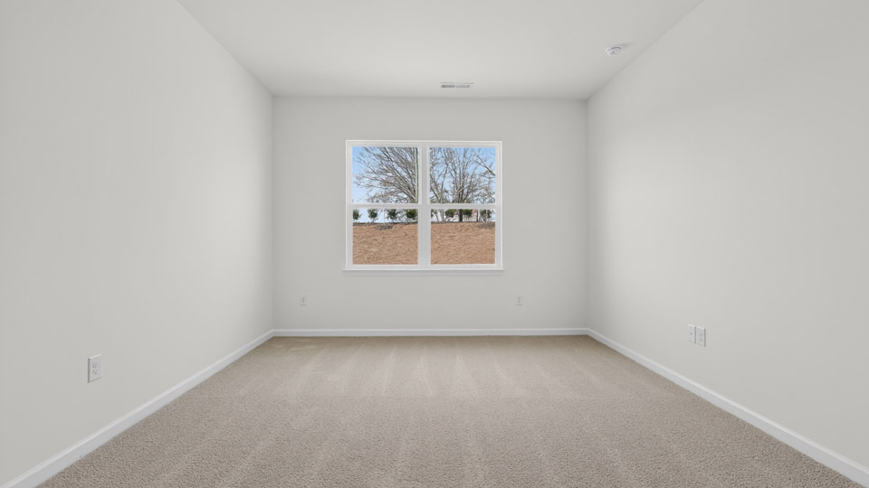 Primary bedroom with carpet floors and windows with access to the primary bathroom