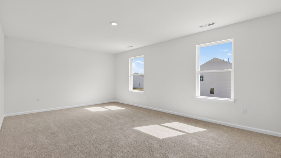 Primary bedroom with carpet floors and windows with access to the primary bathroom