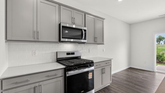 kitchen with quartz counters, kitchen island, pantry, stainless steel appliances