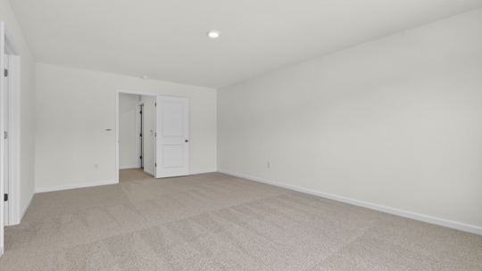 primary bedroom with two windows and carpeting, attached bath