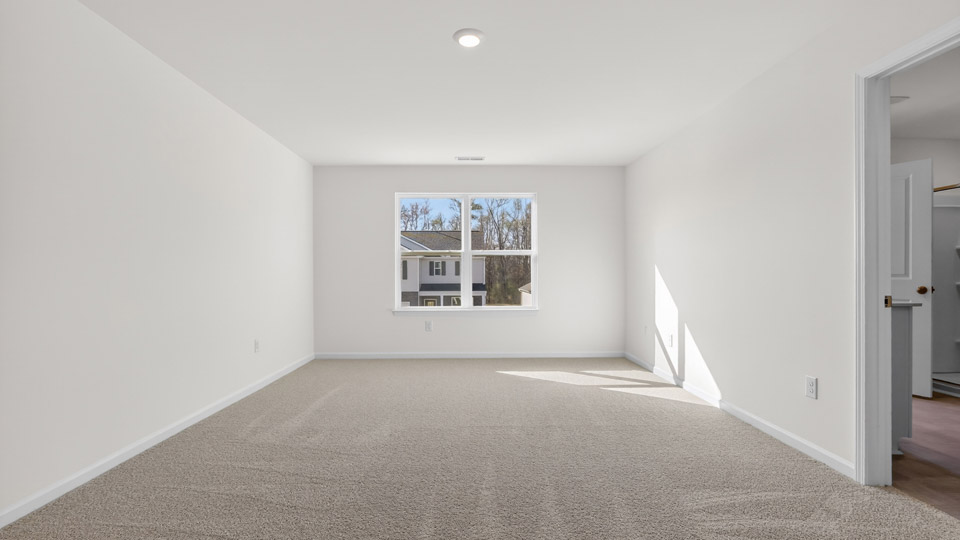 Primary bedroom with carpet floors and windows with access to the primary bathroom