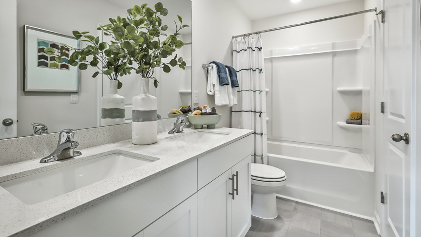 bathroom with tub shower combo and dual vanity and quartz countertops