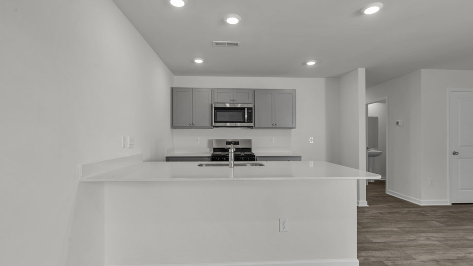 kitchen with quartz counters, kitchen peninsula, pantry, stainless steel appliances