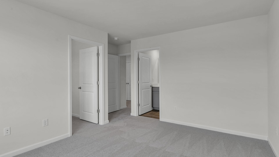 primary bedroom with two windows and carpeting, attached bath