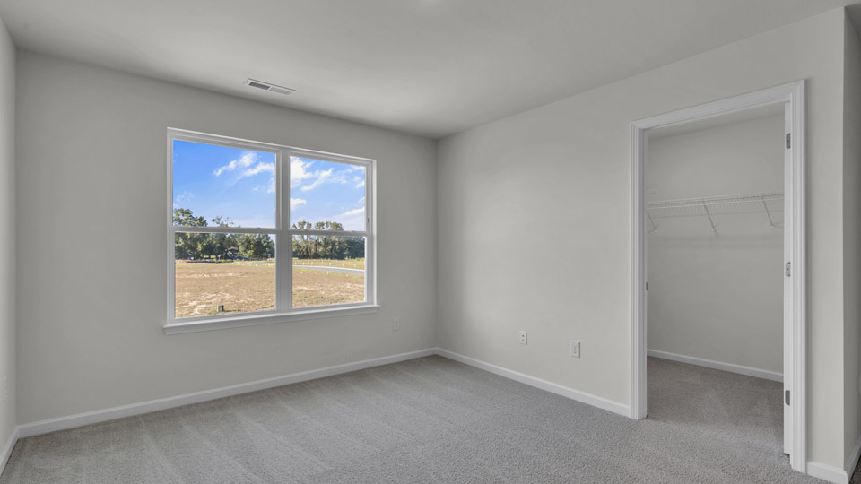 primary bedroom with two windows and carpeting, attached bath