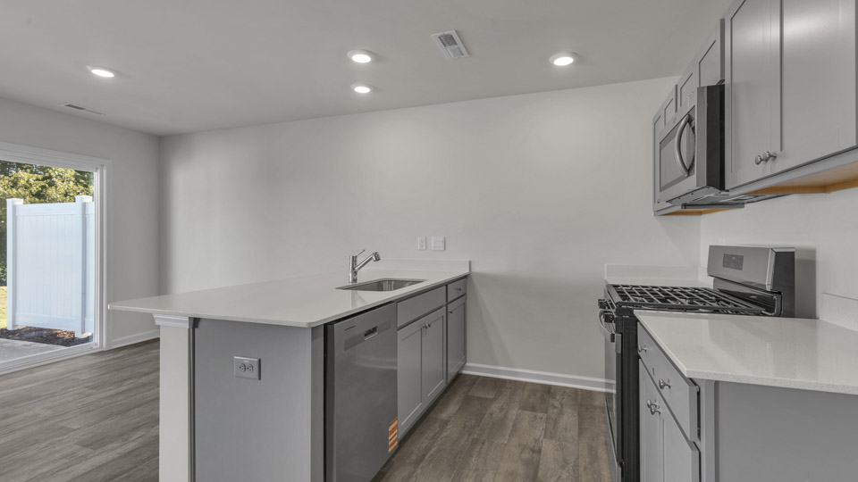kitchen with quartz counters, kitchen peninsula, pantry, stainless steel appliances