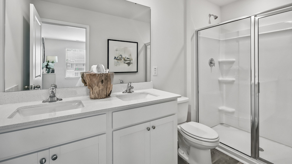 primary bathroom with walk in shower and dual vanity sinks