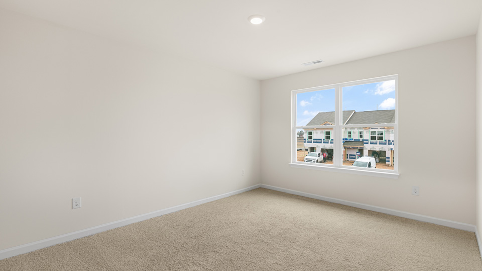 primary bedroom with two windows and carpeting, attached bath