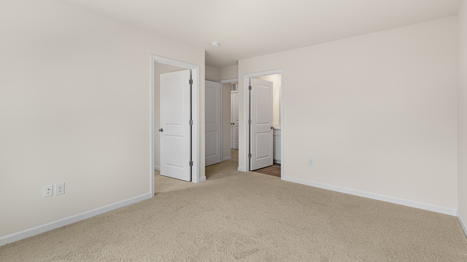 primary bedroom with two windows and carpeting, attached bath