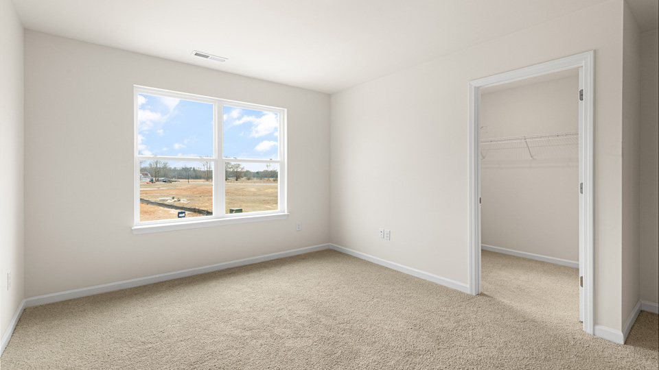 primary bedroom with two windows and carpeting, attached bath