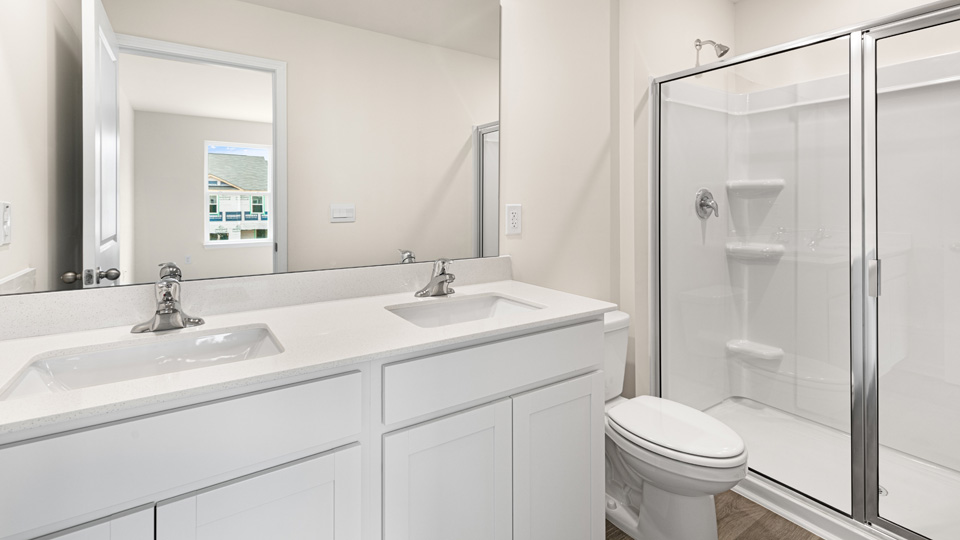 primary bathroom with walk in shower and dual vanity sinks
