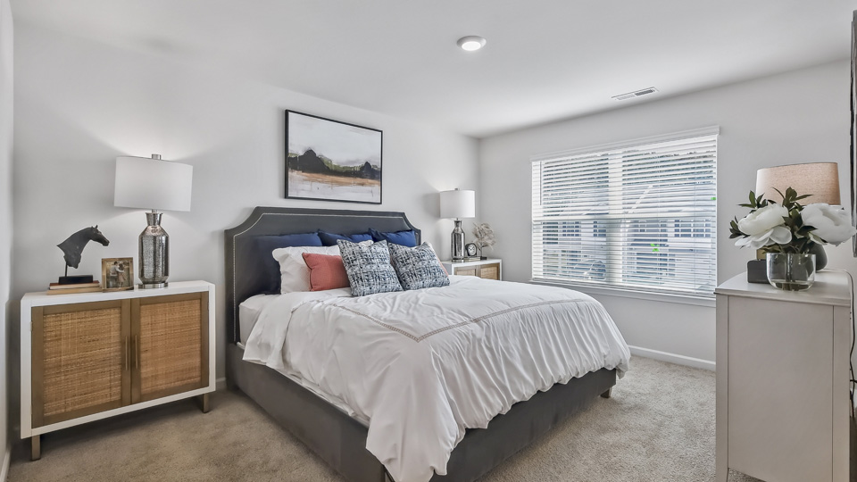primary bedroom with two windows and carpeting, attached bath