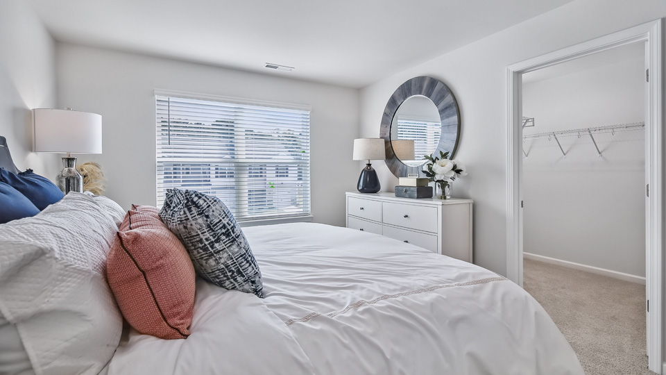 primary bedroom with two windows and carpeting, attached bath