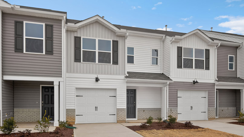 Two story town home with white and gray siding and a garage.