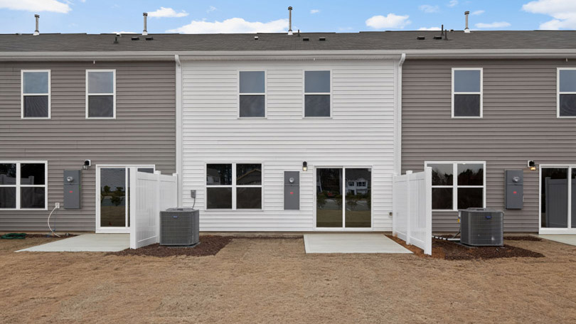 Two story town home with white and gray siding and a back patio
