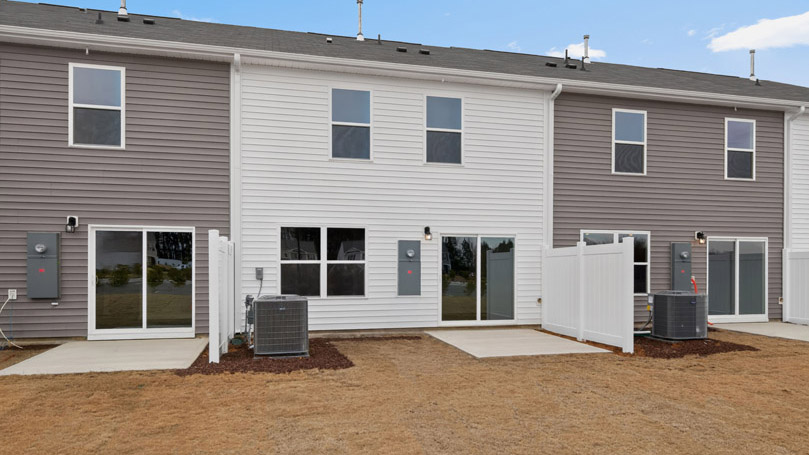 Two story town home with white and gray siding and a back patio