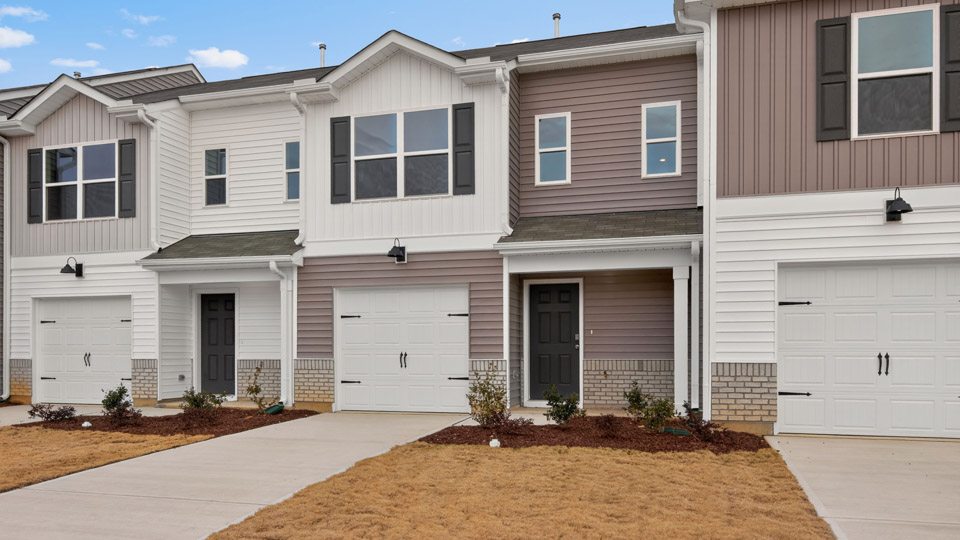 Two story town home with white and brown siding and garage.