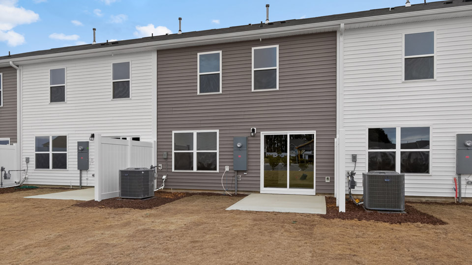 Two story town home with white and brown siding and garage.