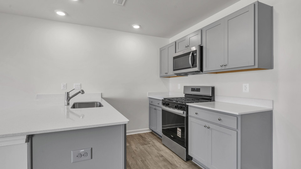 kitchen with quartz counters, kitchen peninsula, pantry, stainless steel appliances