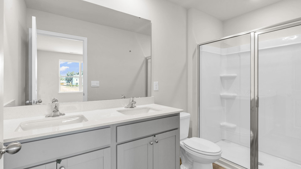 primary bathroom with walk in shower and dual vanity sinks