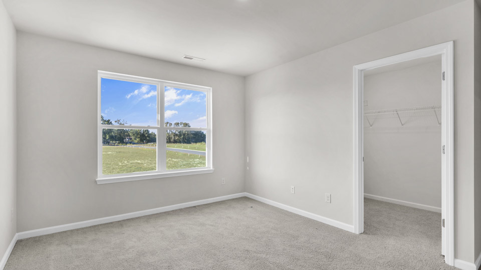 primary bedroom with two windows and carpeting, attached bath