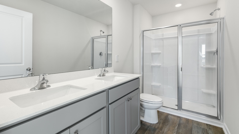 primary bathroom with walk in shower and dual vanity sinks