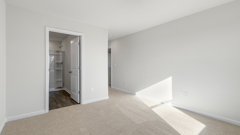 primary bedroom with two windows and carpeting, attached bath