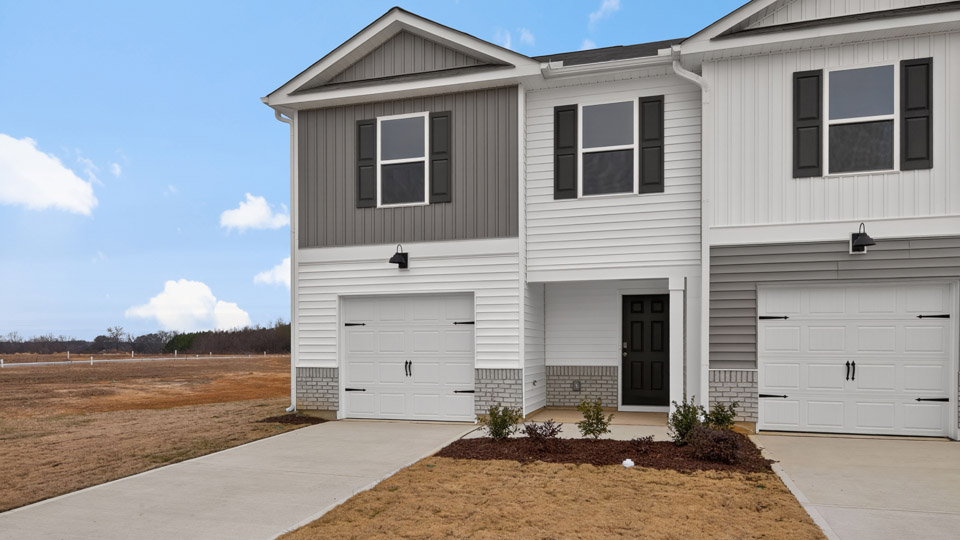 Two story home with gray and white siding and two-car garage.