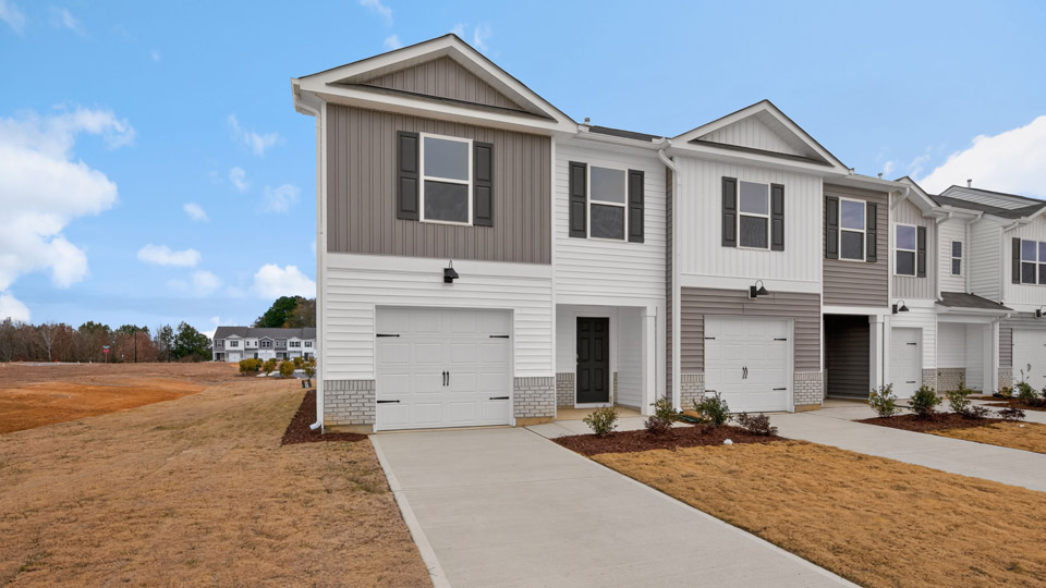 Two story home with gray and white siding and two-car garage.