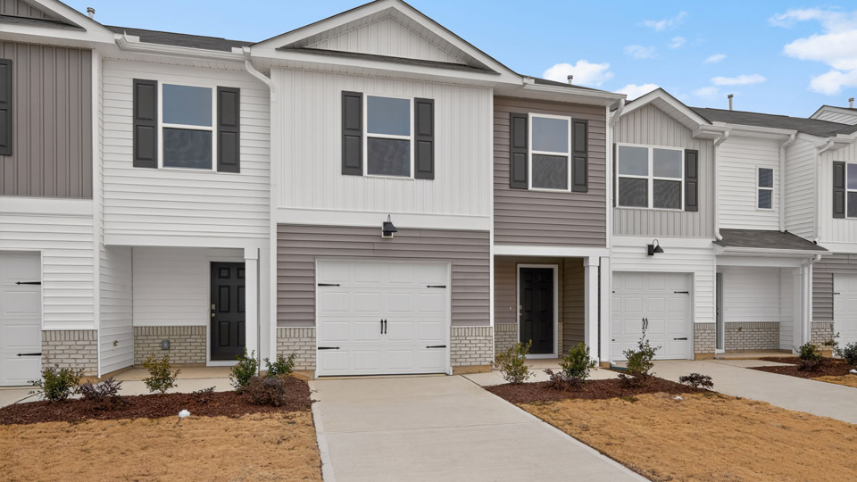 Two story home with gray and white siding and two-car garage.