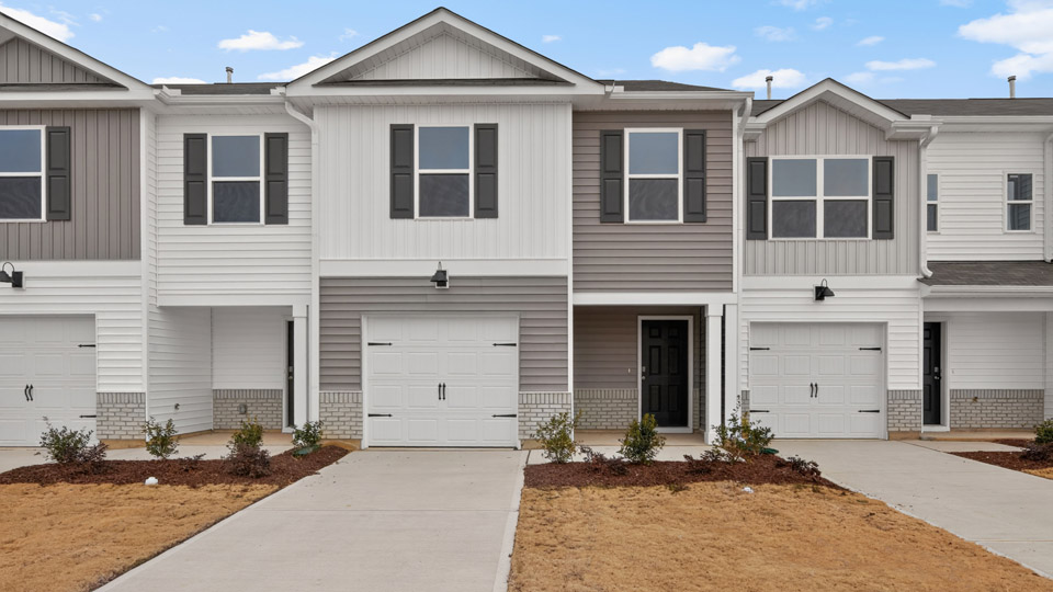 Two story home with gray and white siding and two-car garage.