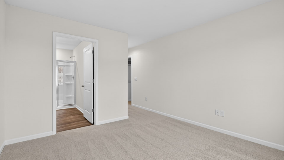 Primary bedroom with carpet floors and windows with access to the primary bathroom